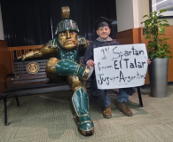 Torres seated next to sparty statue